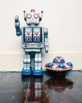 vintage robot toy  with a  toy UFO on a old wooden floor  with reflection 