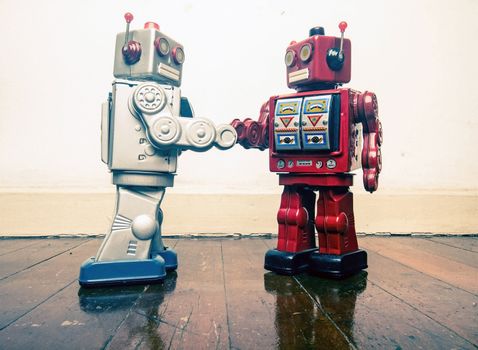 two vintage robot shake hands on a old wooden floor  toned image 