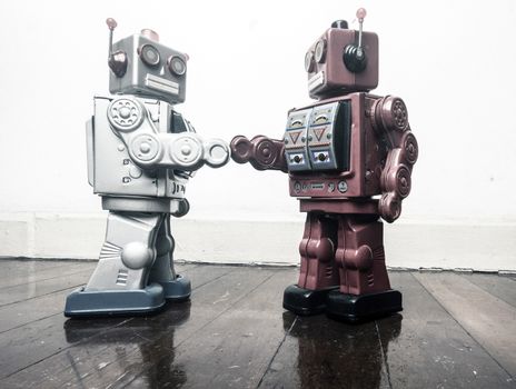 two vintage robot shake hands on a old wooden floor  toned image 
