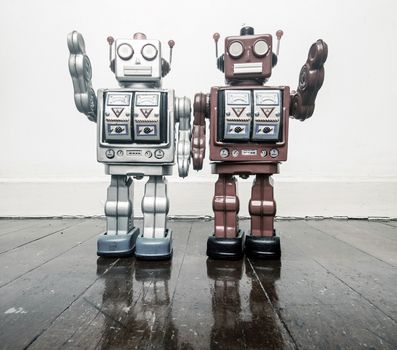 two vintage robots say hi  on a wooden floor toned image 