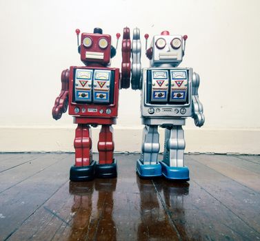 two vintage robot toy happy together on a wooden floor with reflection