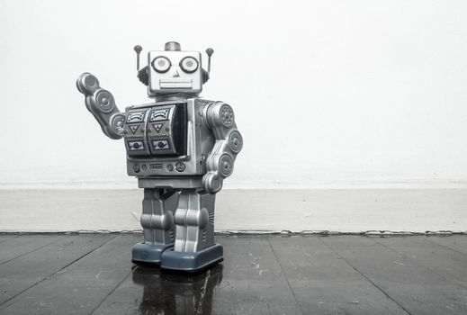 retro silver robot waving hi on an old wooden floor 