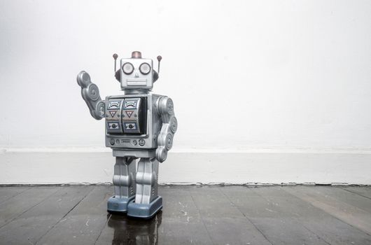 retro silver robot waving hi on an old wooden floor 