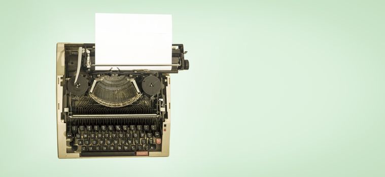 vintage mechanical  typewriter, on a light green background from avove
