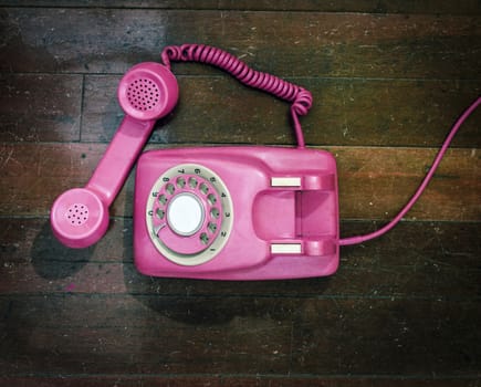 vintage pink phone on a old wooden floor from above 