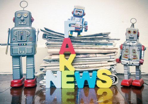 three retro robots  a pile of old newspaper with the word FAKE NEWS on a wooden floor 