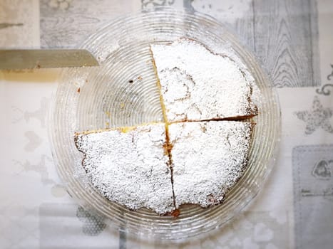 Sweet cake covered with icing sugar cut into slices seen from above