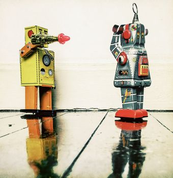 concept gun crime with retro toy robots on a wooden floor 