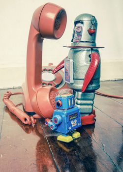  two vintabe robot with old phone on wooden floor