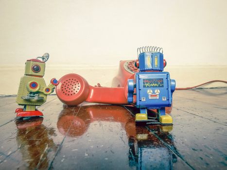  two vintabe robot with old phone on wooden floor