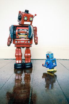 Boss robots looking down on his working robots on wooden floor with reflection