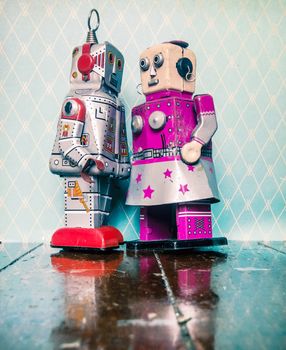 two retro robot toys in love on old wooden floor with reflection 