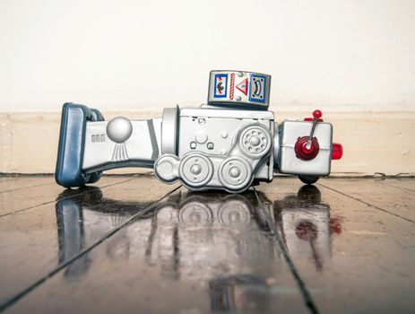 over worked retro silver robot on old wooden floor with reflection