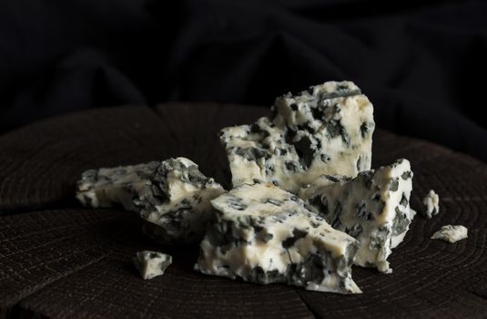 Pieces of danish blue cheese on black wooden background, with copy space