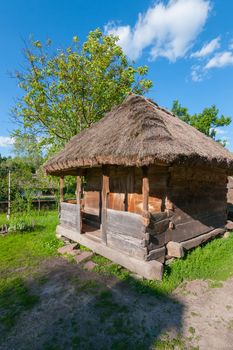 An old wooden house with a thatched roof with walls that have been decayed by time and the entrance door from the boards.