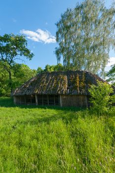 Construction with a thatched roof and walls of rags on a green lawn