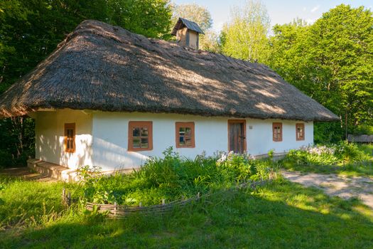 A large authentic Ukrainian hut with clay walls and a thatched roof