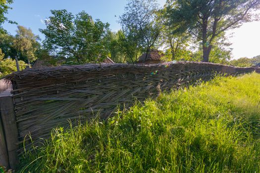 beautifully woven dense wooden daisies near an old house among green herbs. Uzhhorod Ukraine