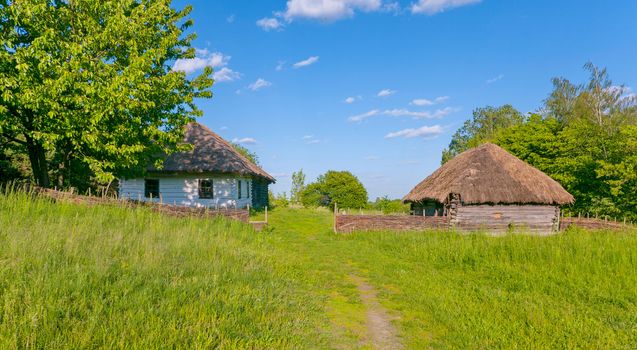 authentic wooden house covered with reeds in the yard under the blue sky