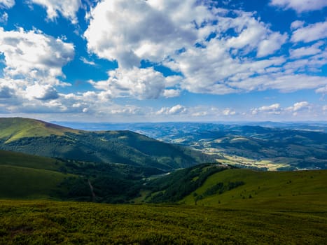 Beautiful big green mountain valley against a blue sky with white clouds