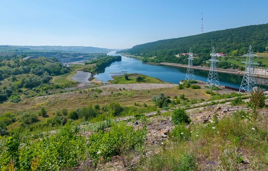 wide Tisza River with electric aids on the shore near a wooded hill