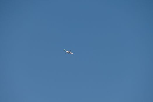 The white plane runs high in the blue sky without any clouds