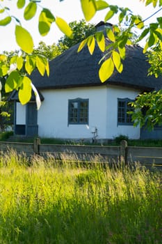 Authentic national Ukrainian hut in the shade of green trees and bushes