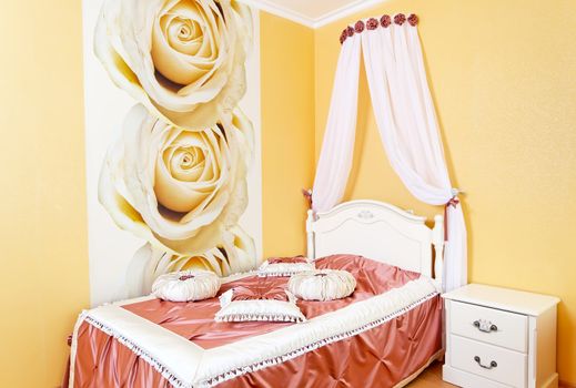 Beautiful bedroom yellow interior with roses and fabric pillows