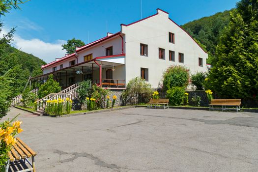 A beautiful cottage with two staircases and entrances and an asphalt platform with benches in front of it