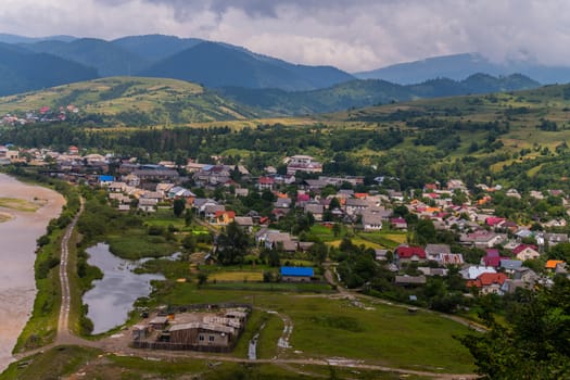 Village village with small houses is located in the shadow of a large gently sloping mountains