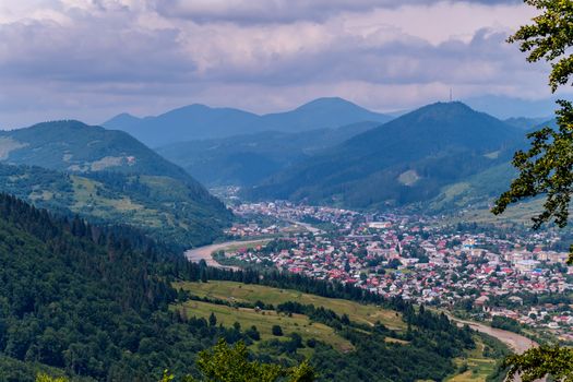 The blue tops of the mountains in the fog, the restless sky in the clouds and a small town with one-story colored houses
