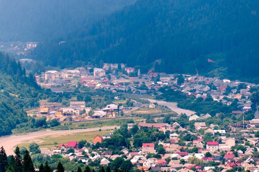 Mountain valley with colorful houses surrounded by a high coniferous forest. The place where the city vanity is unknown