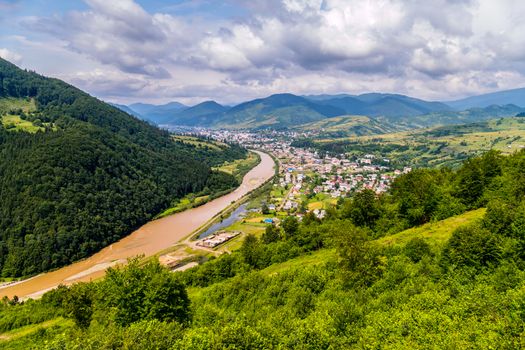 The storm stream carries water from the summits, bending the green mountain near the city in the valley