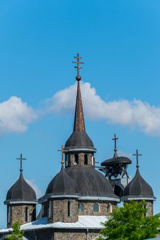 Ancient church with black domes against the blue sky. Made of brown stone. The contrast of color is striking