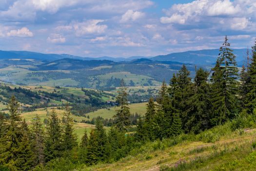 boundless green plains with small mountains in the distance and rural houses between them