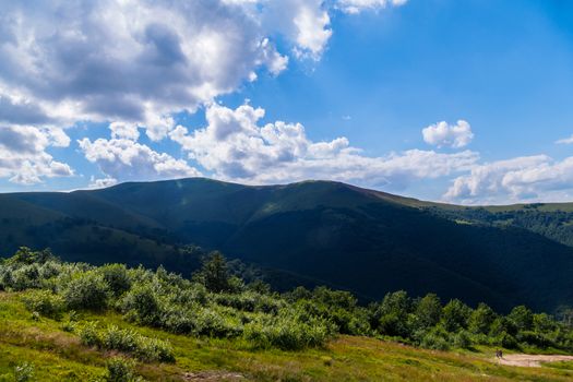 the top of the mountain in the shadow of a large cloud with thickets of bushes and trees