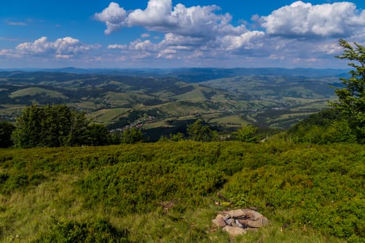 The green playground is overgrown with thick lush grass with a beautiful view of the distance to the picturesque valleys and houses stretching between them stretching out with a long white thread.