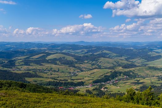 Slender rows of rural houses lying in green mountain valleys. From the top of the slope seeming quite small.