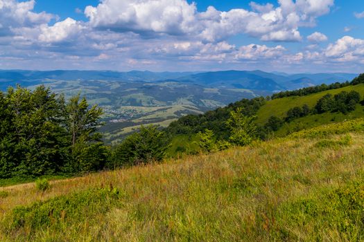 A large rural village with small houses is located in the valley of picturesque green mountains