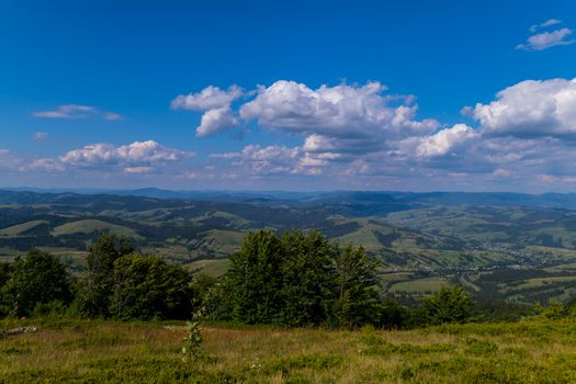 Landscape of mountain peaks and valleys with houses below. Beautiful greenery of trees and grasses and a beautiful purity of heavenly heights.