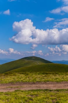 Interesting and entertaining cloud on a blue sky over a small and winding hill
