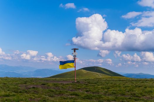 A pointer with a Ukrainian flag set at the peak of a big green mountain