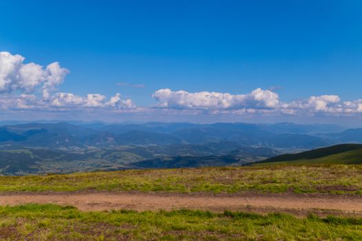 The top view of the huge gently sloping green mountain ranges and the blue boundless sky