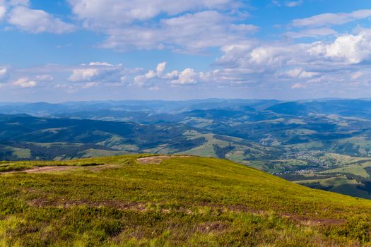 trampled path to the top of the mountain with a view of the hills and the town in the distance