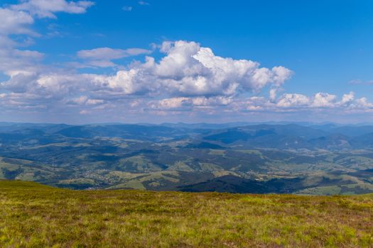 A beautiful view from the top on the huge green mountains and a small rural village at their foothills