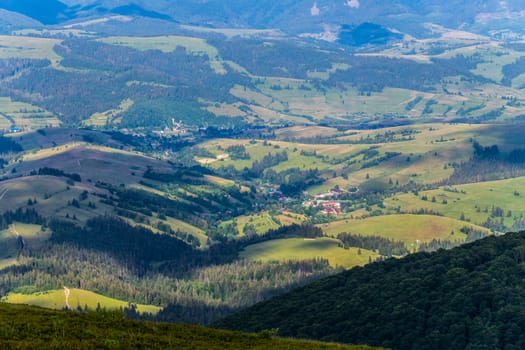 A small authentic rural village at the foot of a mountain range with tall trees