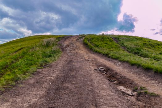 Ornate dodgy mountain road with green grass on the sides leading to the top of the mountain