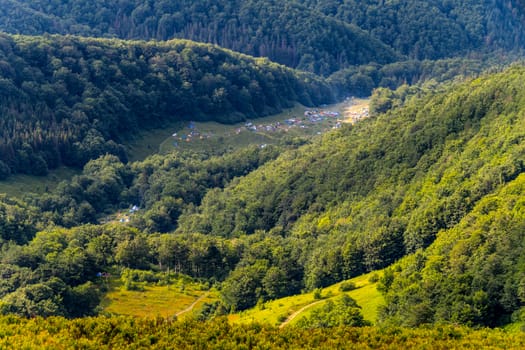 A tent camp lurking in the midst of green forests growing on steep slopes. With cozy meadows and roads.