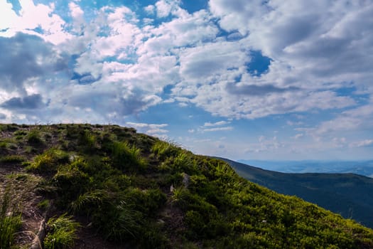 blue sky with fluffy white clouds touching the top of a high mountain