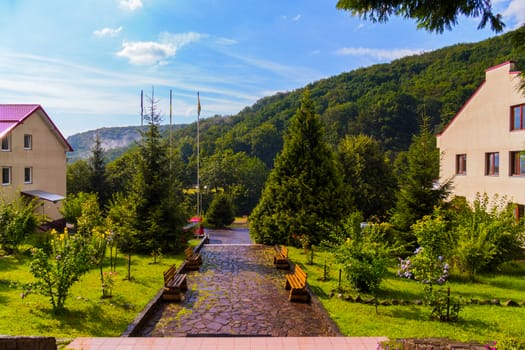 wet the rocky path with benches between the buildings of the hotel complex in the mountains after the rain